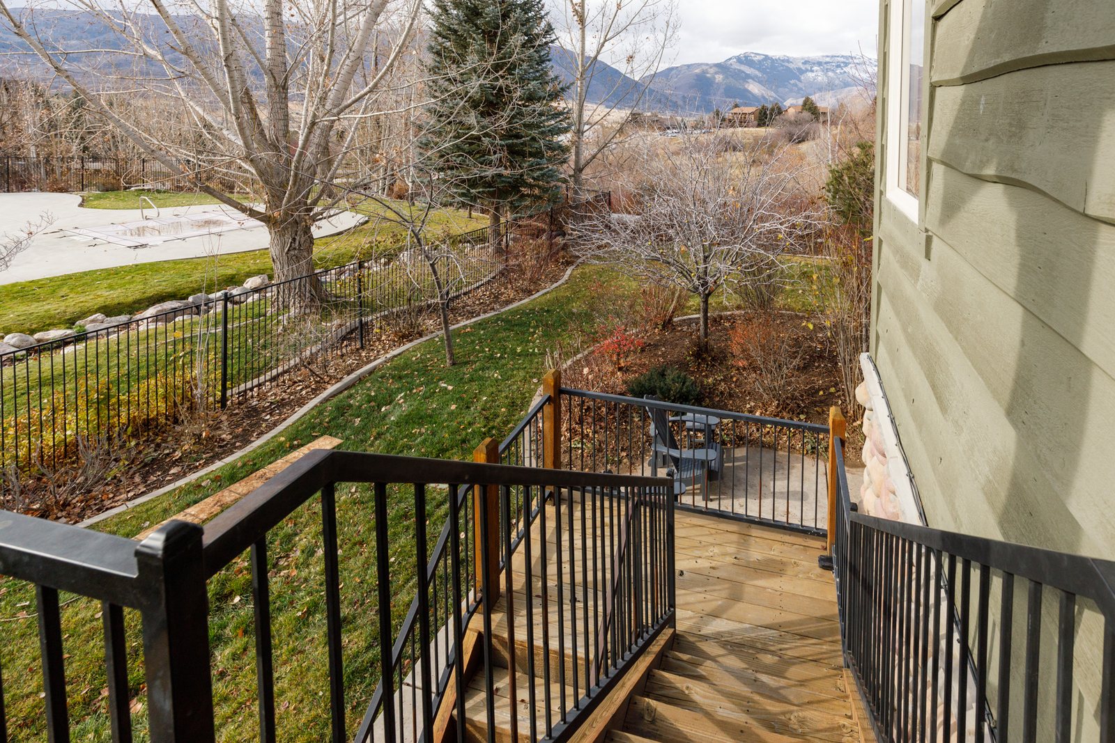 The deck steps running down to the lower patio, with the community pool beyond