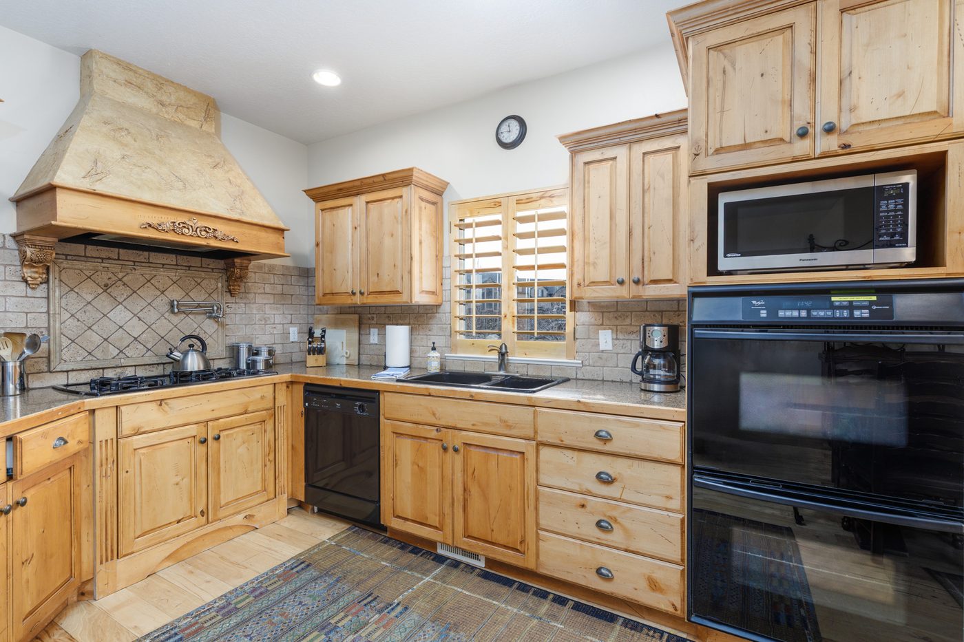 Kitchen with alder cabinetry, granite counters and a stone range hood