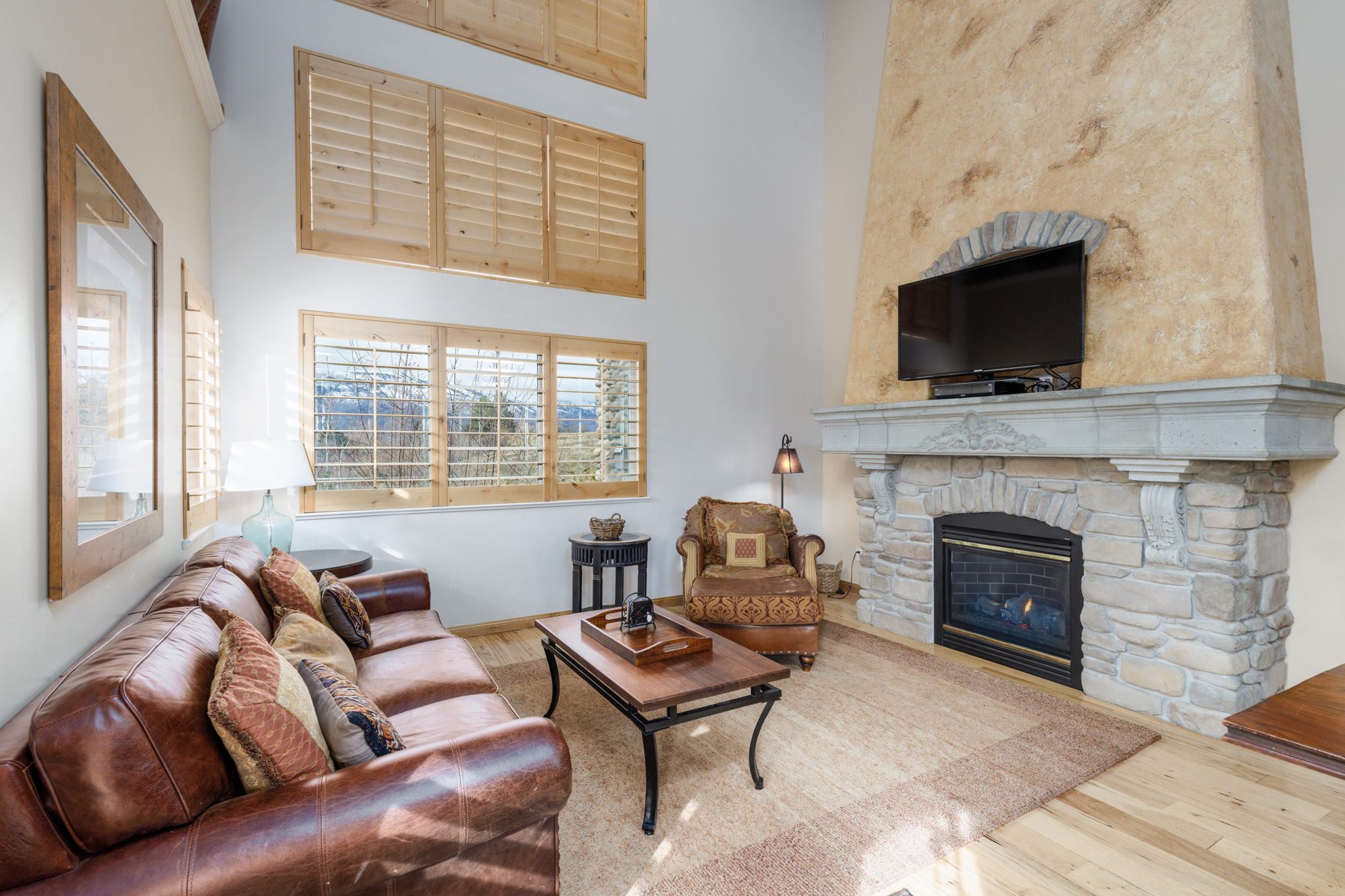 Living room with a two-story river-rock fireplace and carved stone mantel