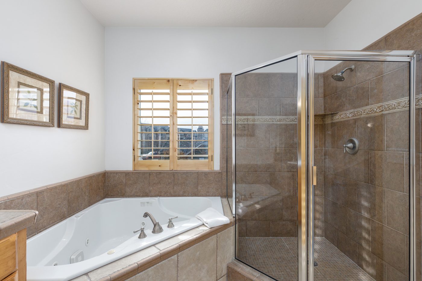 Main-level primary bathroom with a jetted tub and tiled shower