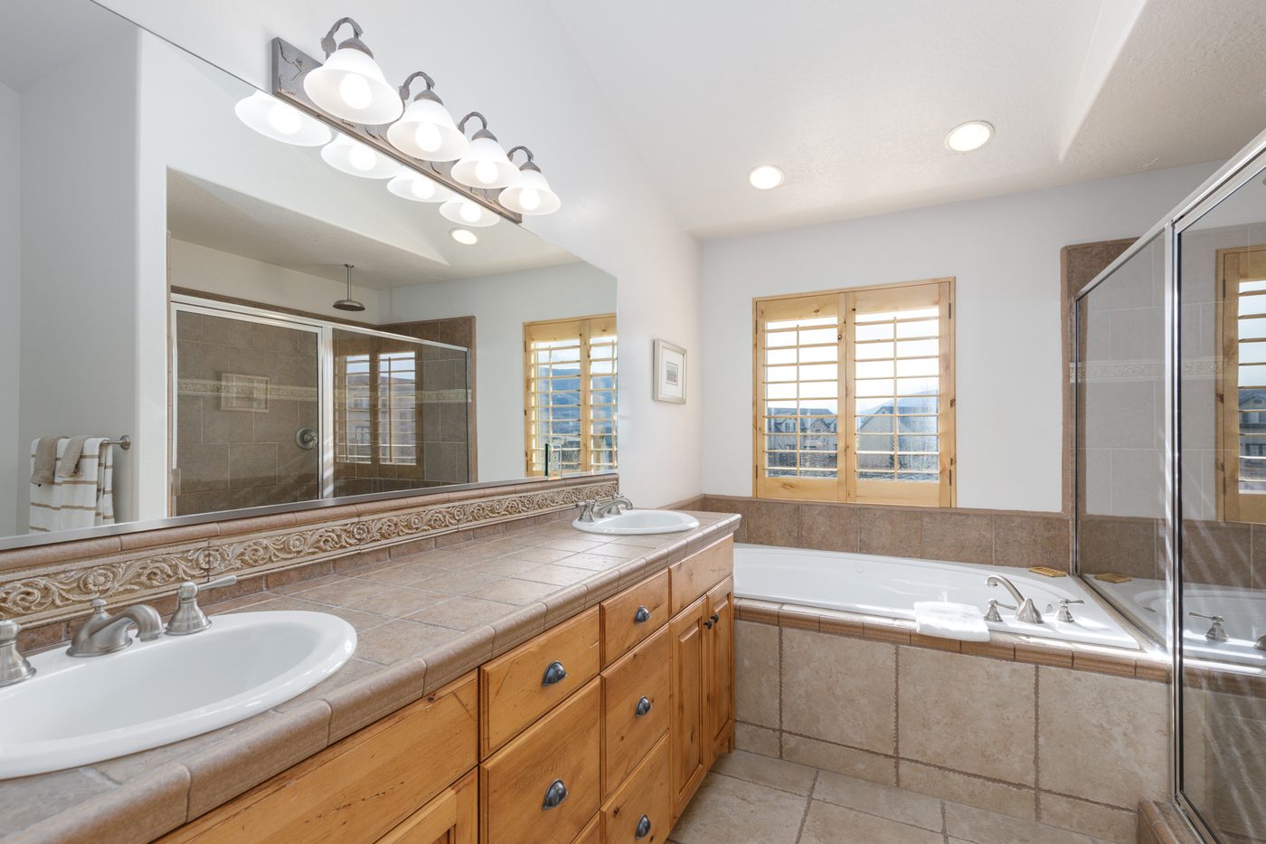Upper primary bathroom with twin sinks, corner tub and separate shower