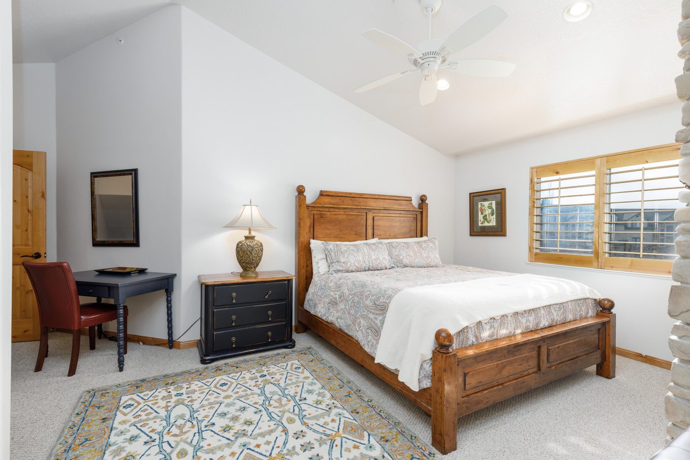 Upper-level primary bedroom with a vaulted ceiling and writing desk