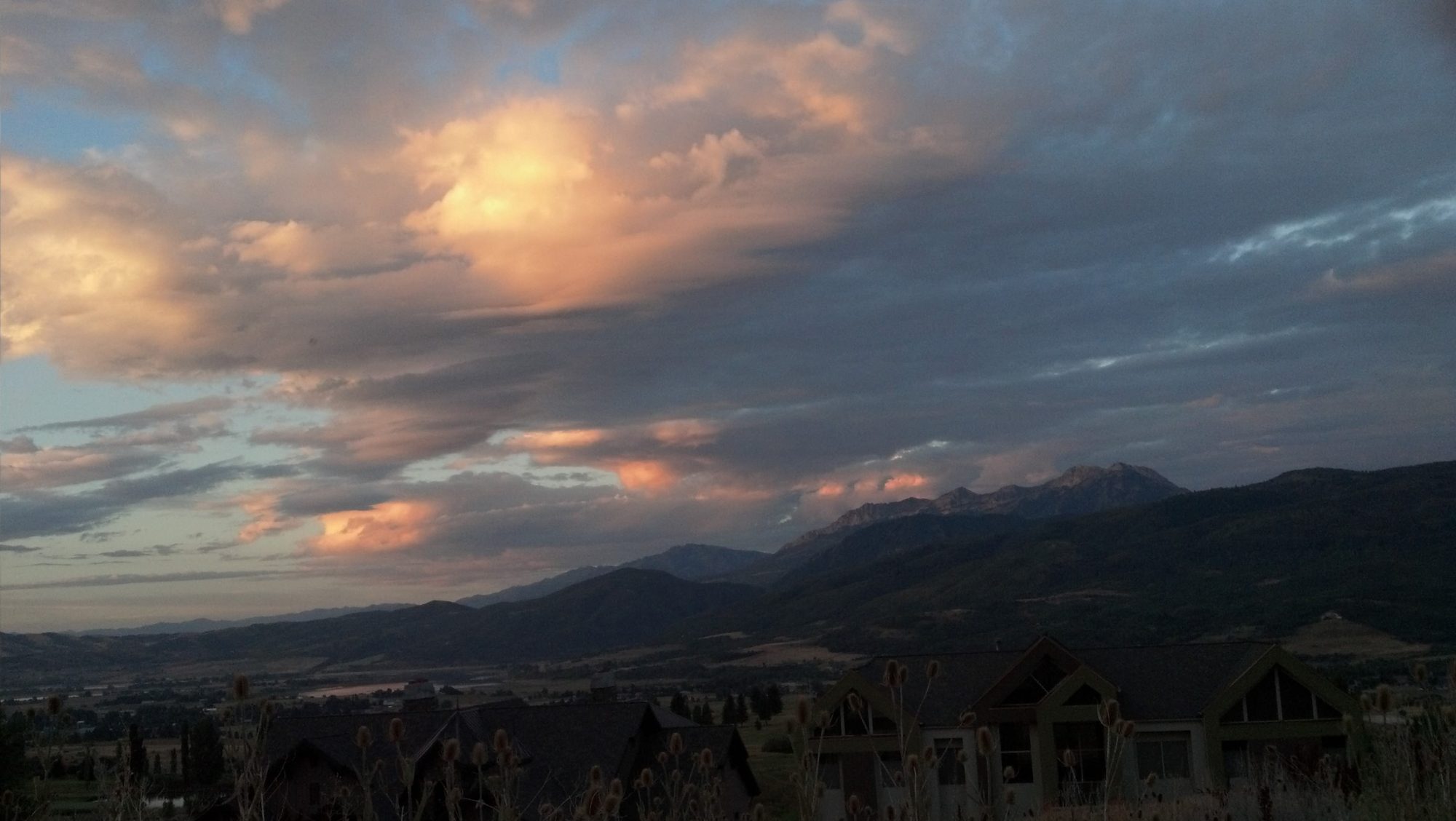 Sunset lighting the clouds orange over Ogden Valley, seen across the rooftops