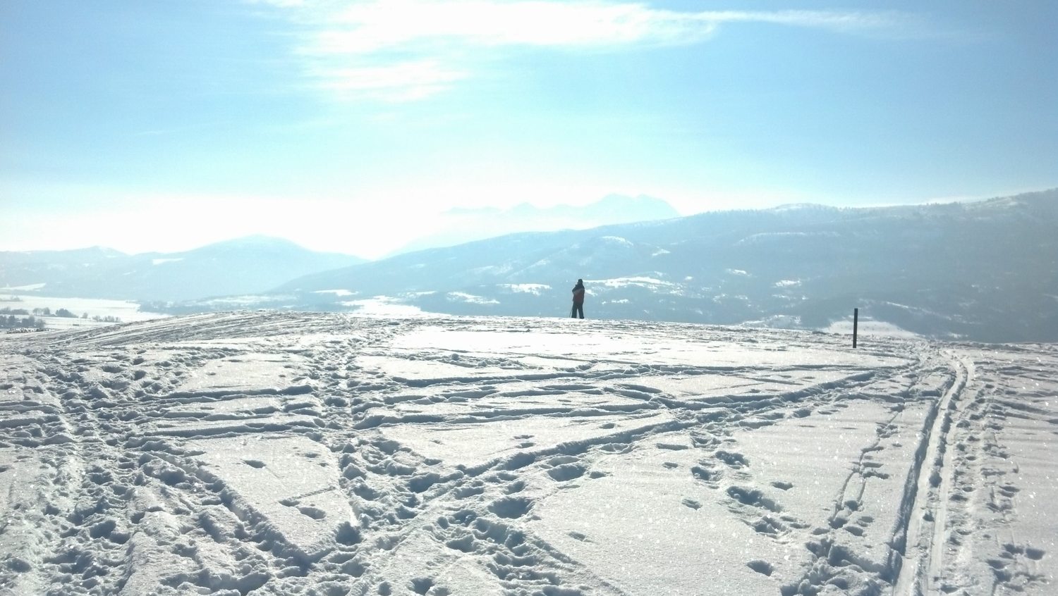 A lone skier out on the open snowfield of the golf course beside the townhome, ski tracks running across it